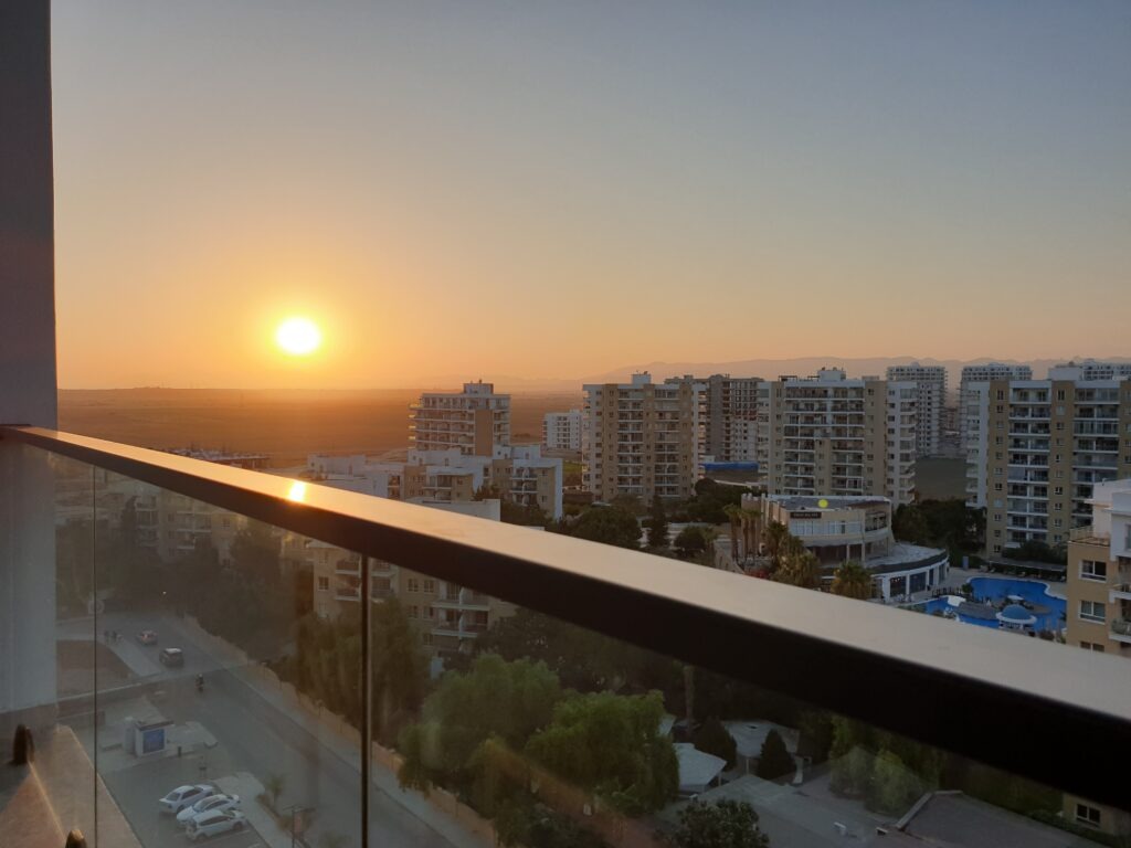 Sonnenuntergang über einer Stadtsilhouette mit modernen Gebäuden.
