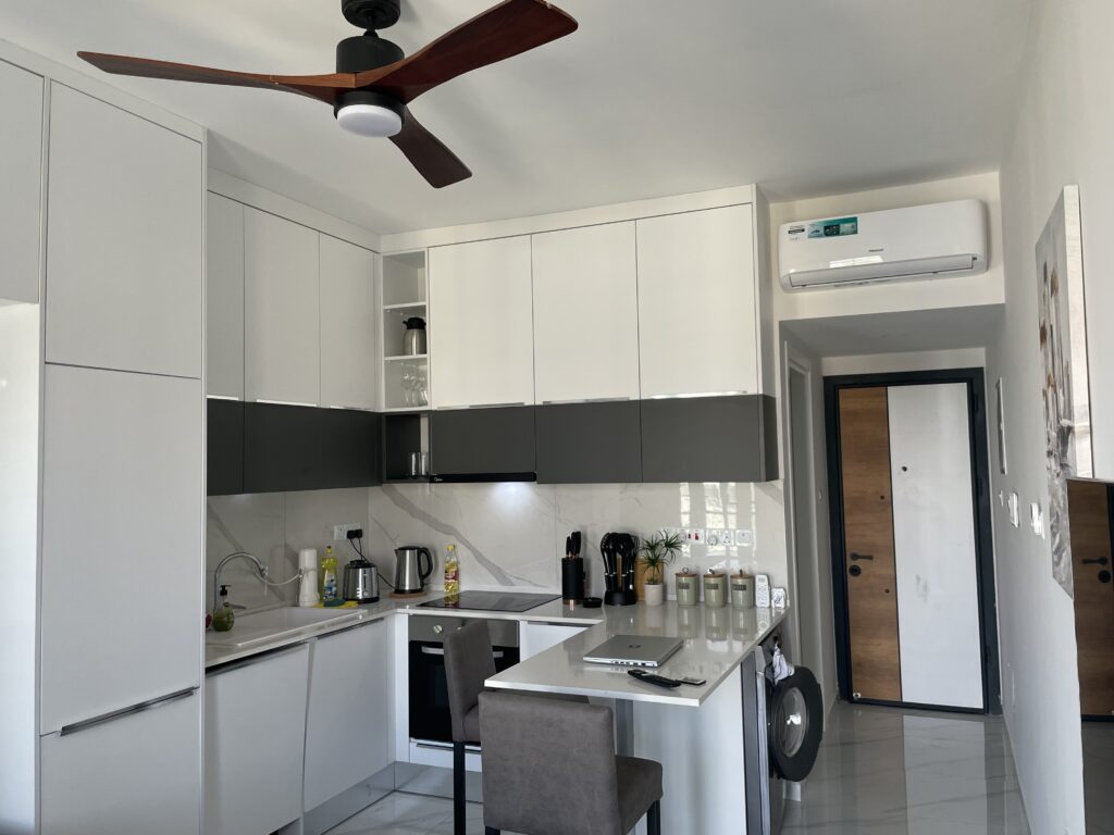 Moderne Küche mit weißen und grauen Schränken, Bartresen und Kühlschrank.