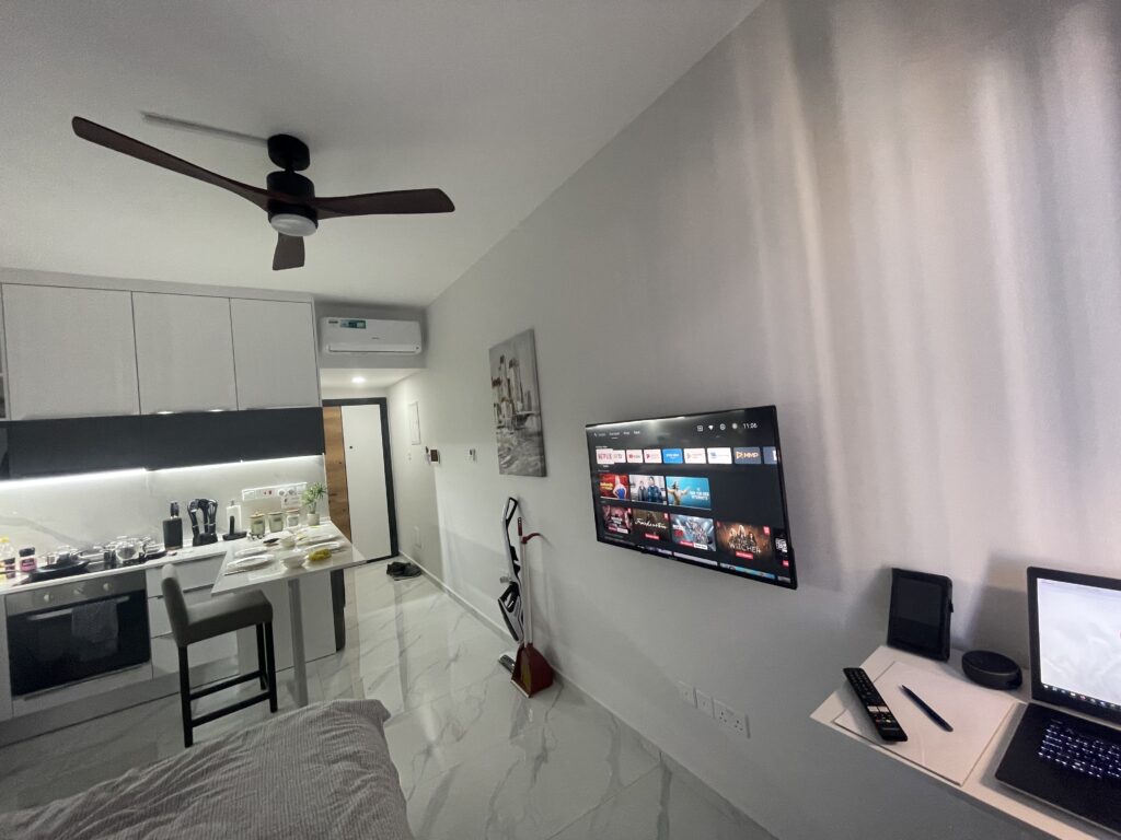 Moderne Wohnung mit Küchenzeile, Essbereich, Wand-TV und Schreibtisch.