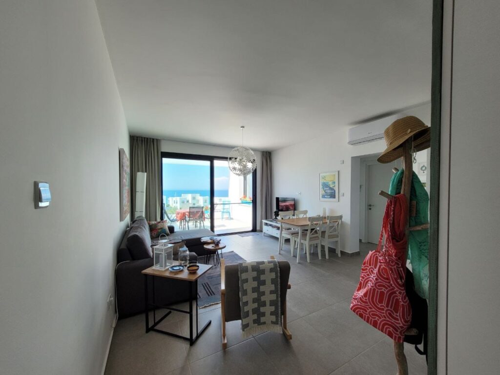 Wohnzimmer mit Balkonblick auf das Meer, Möbel und Dekoration sichtbar.