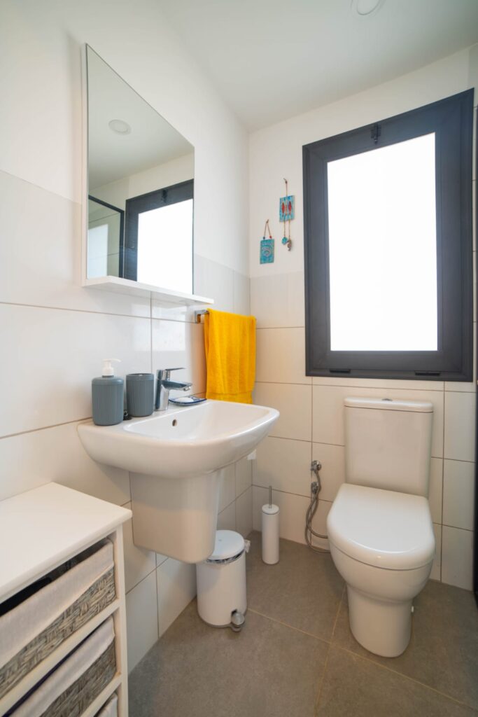 Modernes Badezimmer mit Waschbecken, WC, Spiegel und Fenster.