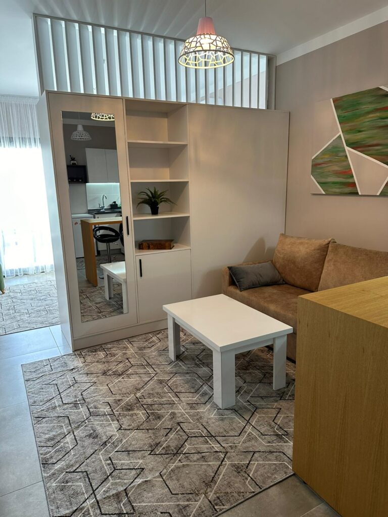 Wohnzimmer mit Couch, Tisch, Regal und abstrakter Wanddekoration.