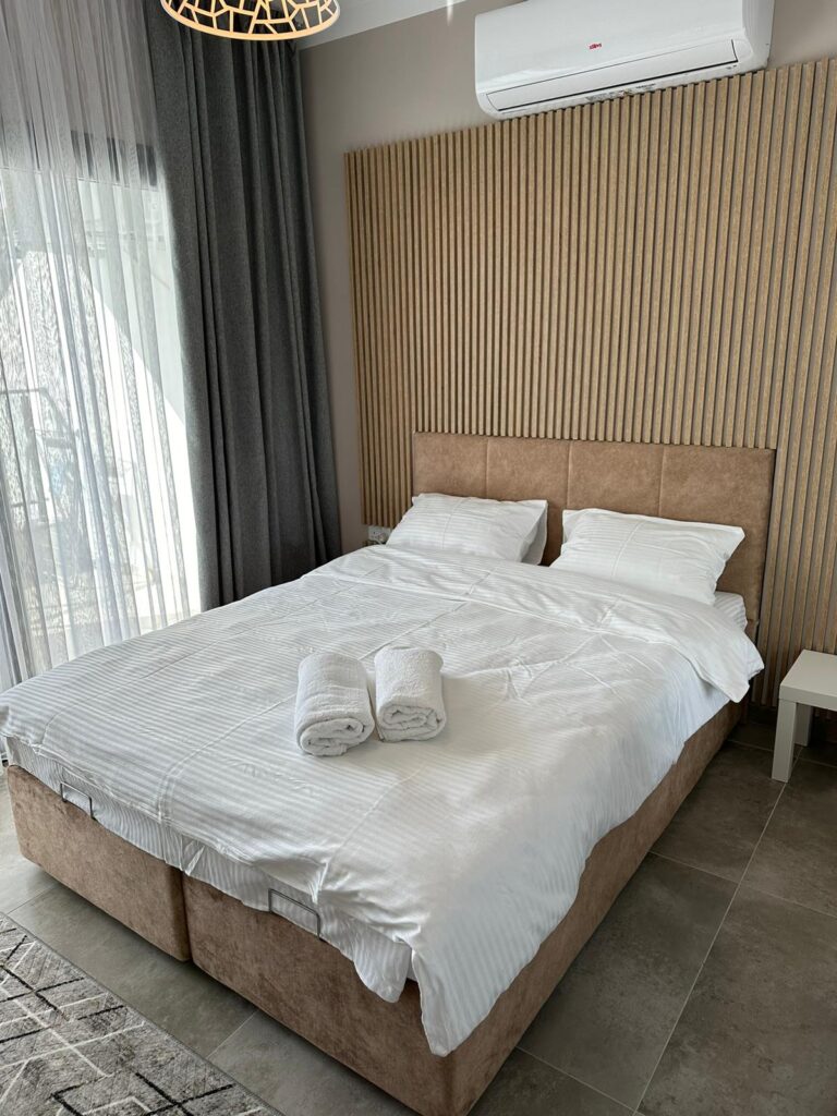 Ein Doppelbett mit weißen Bettwäsche und Handtüchern in einem modernen Schlafzimmer.