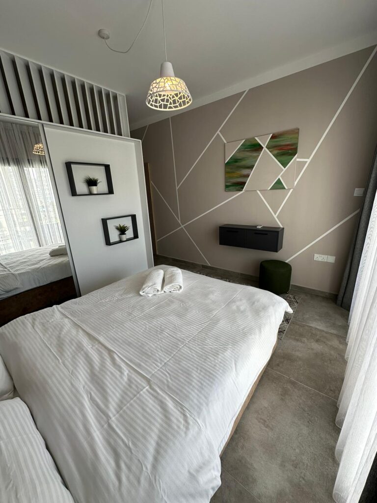 Helles Schlafzimmer mit Doppelbett, moderner Dekoration und Kunstwerk an der Wand.