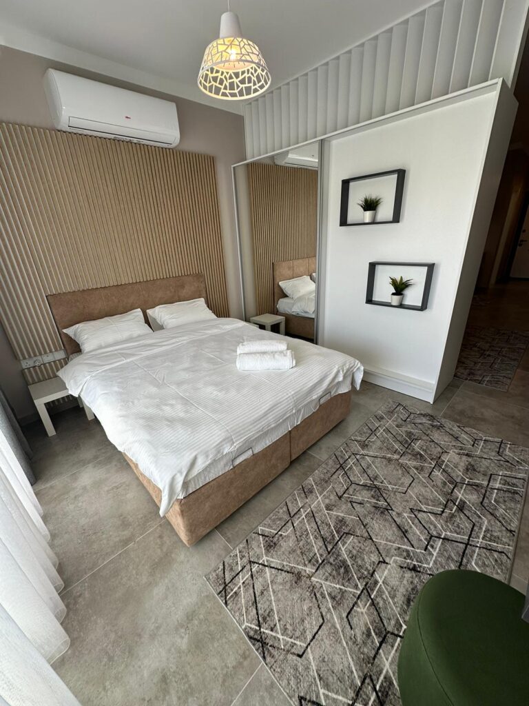 Schlafzimmer mit Doppelbett, Spiegel und modernen Wandbildern.