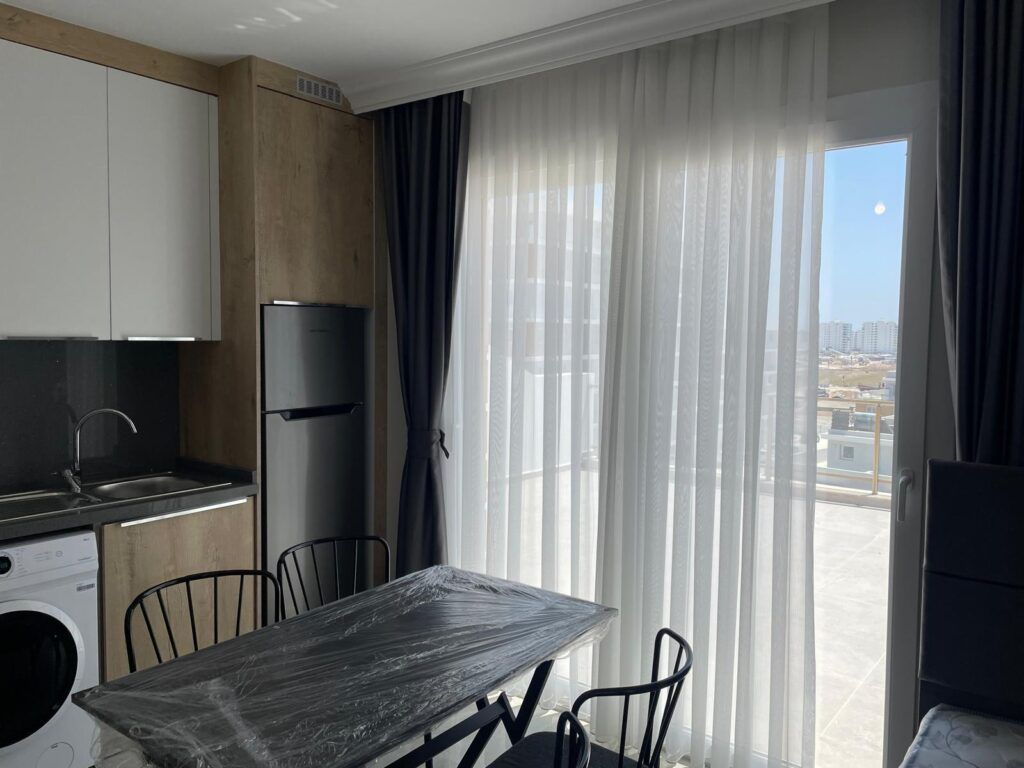 Küche und Essbereich mit Tisch, Stühlen und großer Fensterfront.