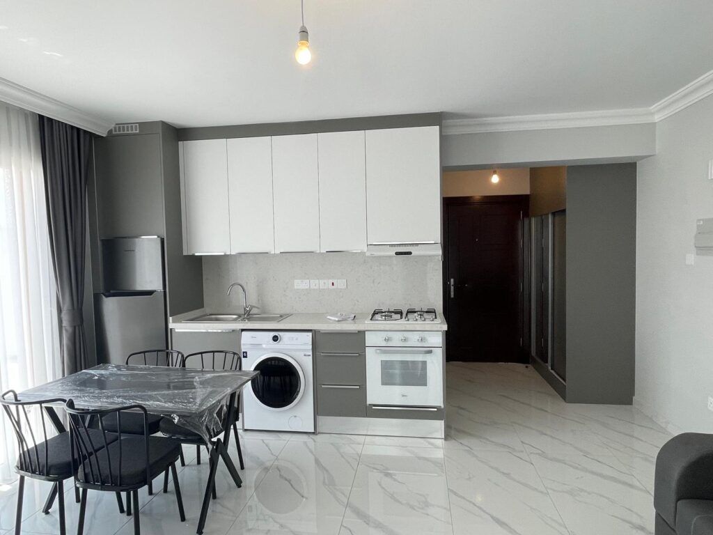 Moderne Küchenzeile mit Herd, Kühlschrank und Essbereich aus schwarzem Metall.