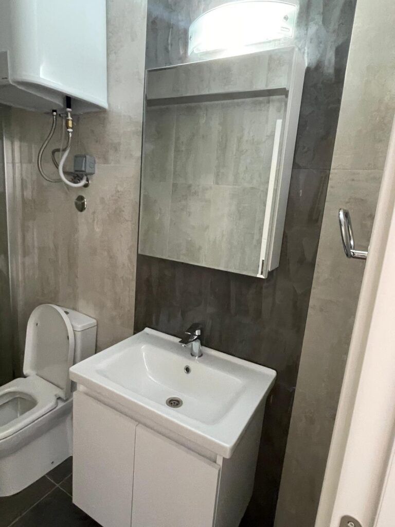 Kleines Badezimmer mit Toilette, Waschbecken und Spiegel.