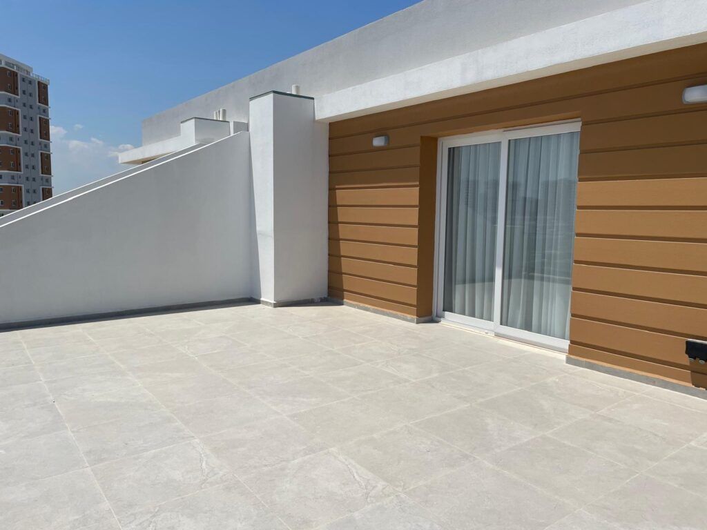 Dachterrasse mit Fliesen und großen Fenstern zur Wohnräume.