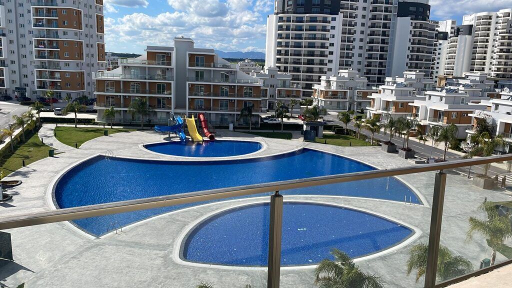 Blick auf einen Pool mit Rutschen und umliegenden Wohngebäuden.